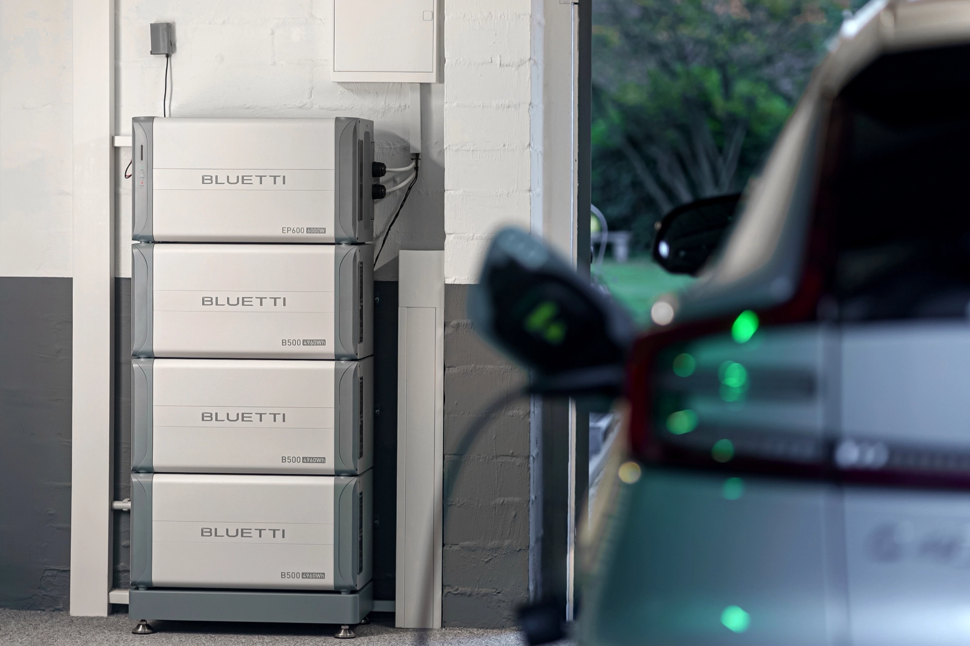 Magazyn energii BLUETTI EP600 z dodatkowymi bateriami B500 w garażu, współpracujący z ładowaniem samochodu elektrycznego